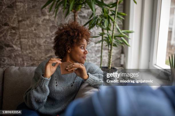 mother sitting on the sofa with her son and eating chocolate - chocolate stockfoto's en -beelden