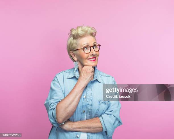 nachdenklich senior frau mit hand am kinn - farbiger hintergrund stock-fotos und bilder