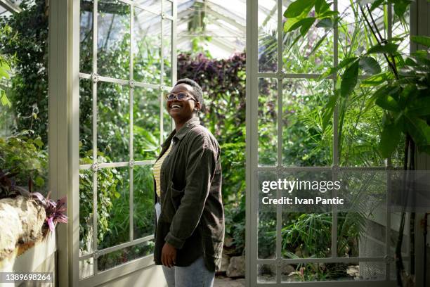 feliz jovem afro-americana explorando um jardim de estufa local - jardim botânico - fotografias e filmes do acervo