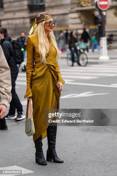 Guest wears gold / green / blue / red print pattern silk scarf on the head, black sunglasses from Gucci, a gold long sleeves / V-neck / wrap midi...