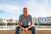 Portrait of smiling man relaxing by the riverbank in Tavira, Algarve, Portugal