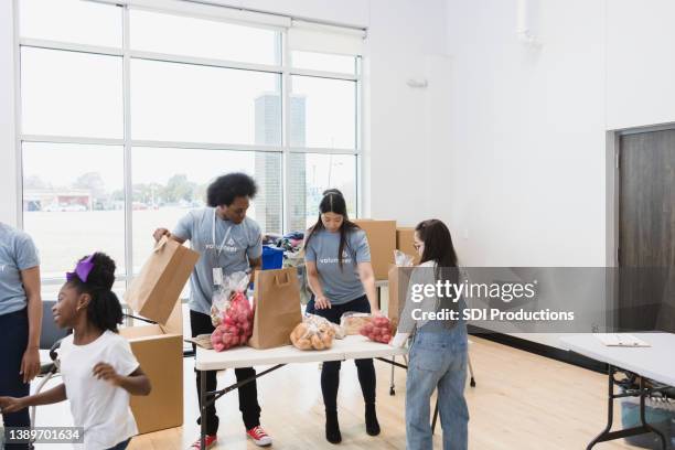 diverse volunteers sort donated food at community event - kids at community center stock pictures, royalty-free photos & images