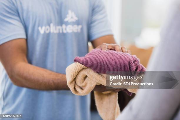 unrecognizeable person hands clothing items to someone - 過頭穿毛線衫 個照片及圖片檔