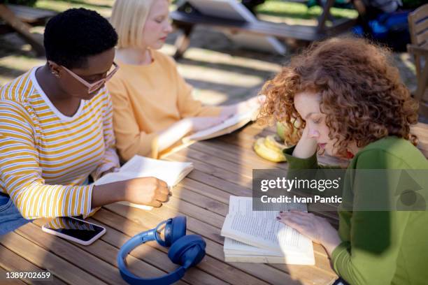 high angle view of a diverse group of female students having a book club together outdoors - reading books club stockfoto's en -beelden
