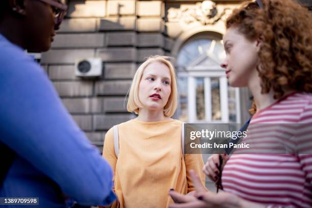 three female adult students talking to each other outdoors - 20s talking serious bildbanksfoton och bilder