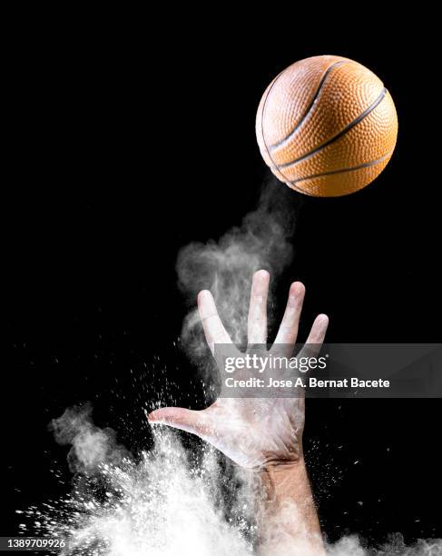 hands of a basketball player catching a ball on a black background. - ballon rebond stock-fotos und bilder