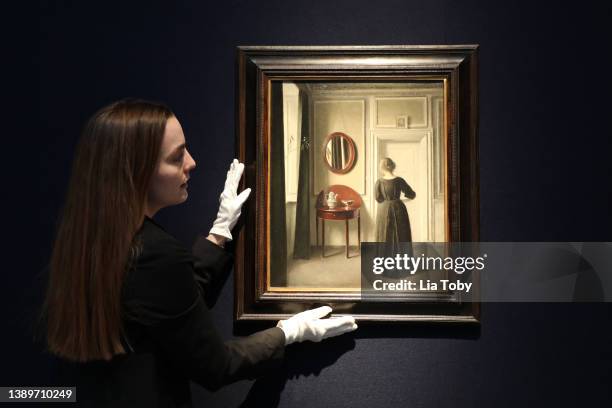 Staff member handles An Interior with an Oval Mirror, by Vilhelm Hammershoi ahead of the auction of the collection of Anne H Bass at Christie's on...