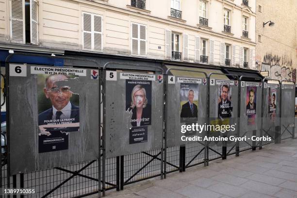 Woman walks past official campaign posters of the candidates for the 2022 presidential election displayed on billboards next to a polling station on...