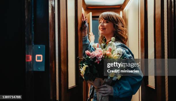 beautiful young woman holding a bouquet of flowers standing in the elevator - elevator doors stock pictures, royalty-free photos & images
