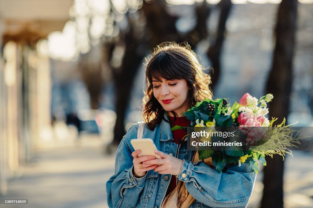Portrait of a Happy Woman Walking in a City With a Bouquet of Flowers