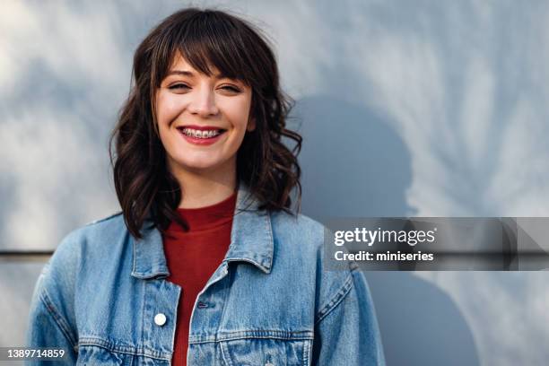 hermosa mujer apoyada contra una pared y sosteniendo flores - banda fotografías e imágenes de stock