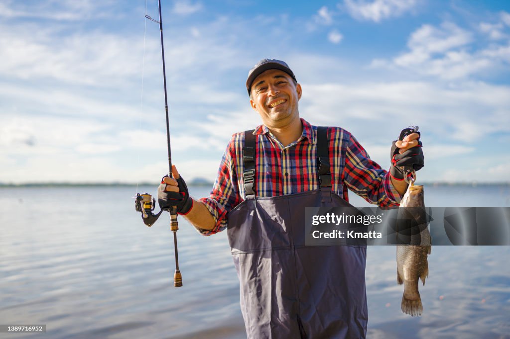 A man holding out a fish that he caught.