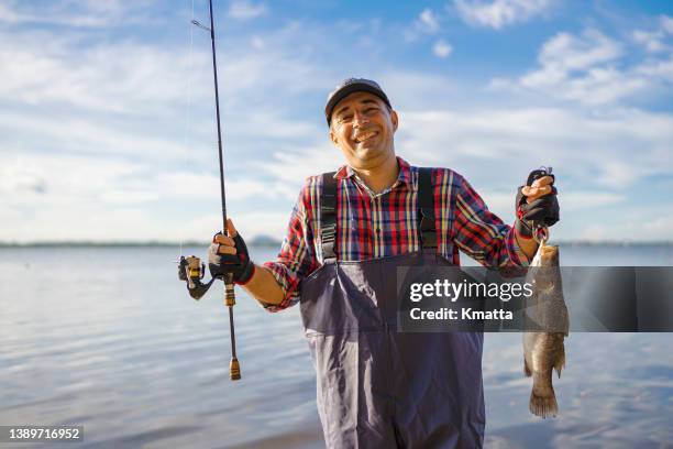 a man holding out a fish that he caught. - fisher man imagens e fotografias de stock