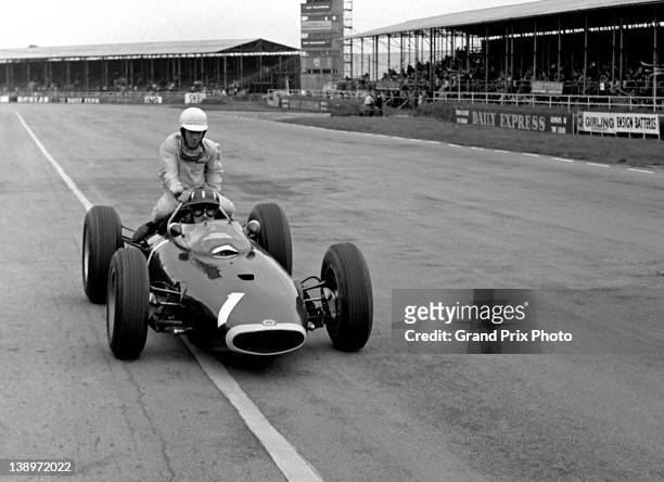 Richie Ginther of the United States catches a ride back to the pits on top of the Owen Racing Organisation BRM P57 BRM V8 of his team mate Graham...