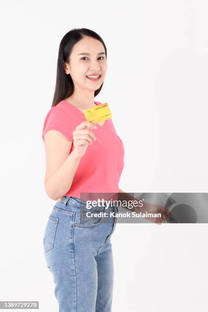 young woman holding credit card while standing against white background - tarjeta de lealtad fotografías e imágenes de stock