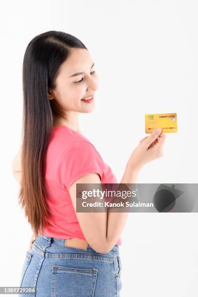 young woman holding credit card while standing against white background - loyalty cards stock pictures, royalty-free photos & images