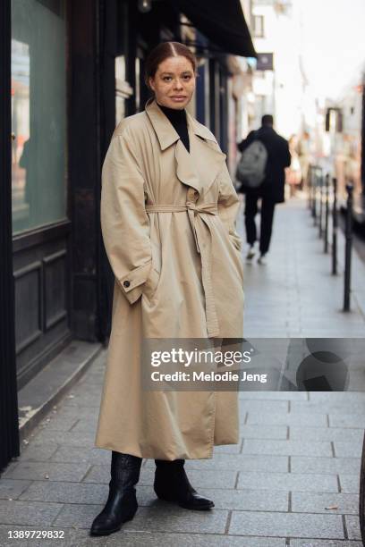 Model Odile Gautreau wears a tan belted trench coat, black leather cowboy boots after the Ester Manas show at Espace Commines during Paris Fashion...