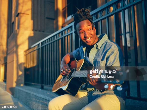 young man playing guitar in the city - busker stock pictures, royalty-free photos & images