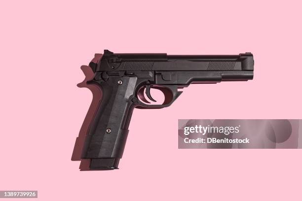 black gun with direct light and hard shadow on pink background. murder, violence, gun, shooting, police, bodyguard, hitman and army concept. - revolver-with-silencer stock-fotos und bilder