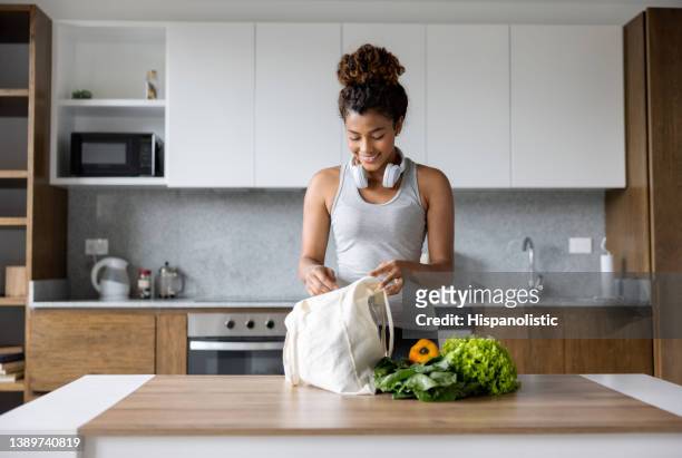 mujer desempacando los comestibles en casa después de comprar en el supermercado - reusable bag fotografías e imágenes de stock