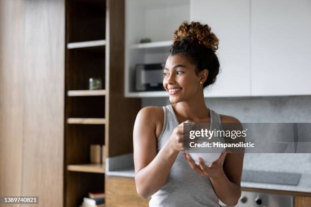 happy woman at home eating a bowl of cereal for breakfast - porridge stock pictures, royalty-free photos & images
