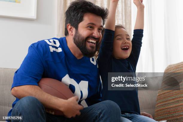 father watching sport game with daughter - american football tv stock pictures, royalty-free photos & images