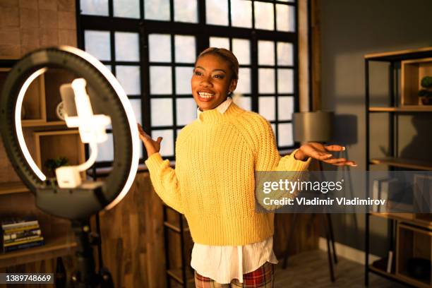 an animated female influencer chatting to a webcam on her mobile - influencer marketing stockfoto's en -beelden