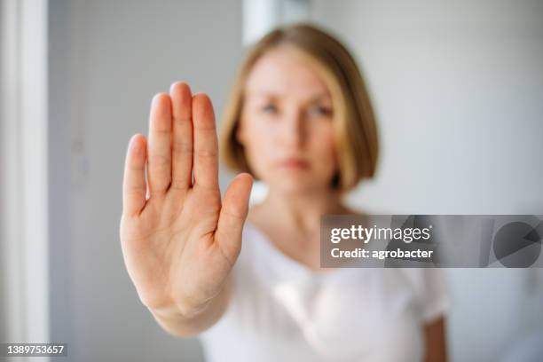 strong young lady extending hand saying no to harassment abuse - afwijzing stockfoto's en -beelden