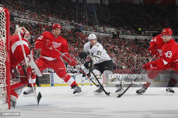 Darren Helm of the Detroit Red Wings takes the puck while Jonathan Ericsson defends Steve Ott of the Dallas Stars and Joey MacDonald tends net during...