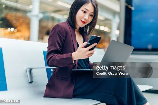 businesswoman on business trip with smart phone and laptop - 日本人　空港 ストックフォトと画像