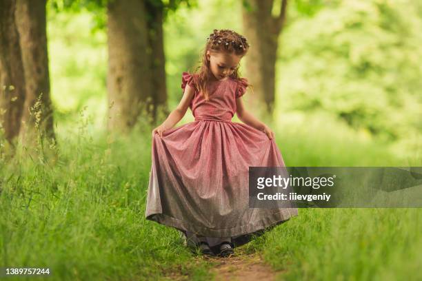 little happy girl in a pink dress on background of spring nature. child is playing in the meadow. vivid emotions. childhood concept. rest on nature. summer vacations. green grass. stylish clothes - sweet little models stock pictures, royalty-free photos & images