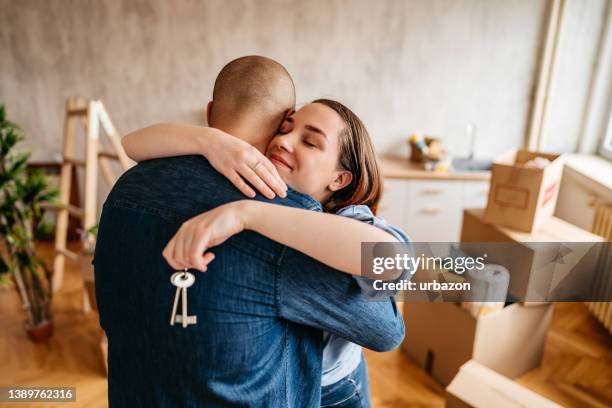 joyful young couple embracing in new apartment - home ownership keys stock pictures, royalty-free photos & images