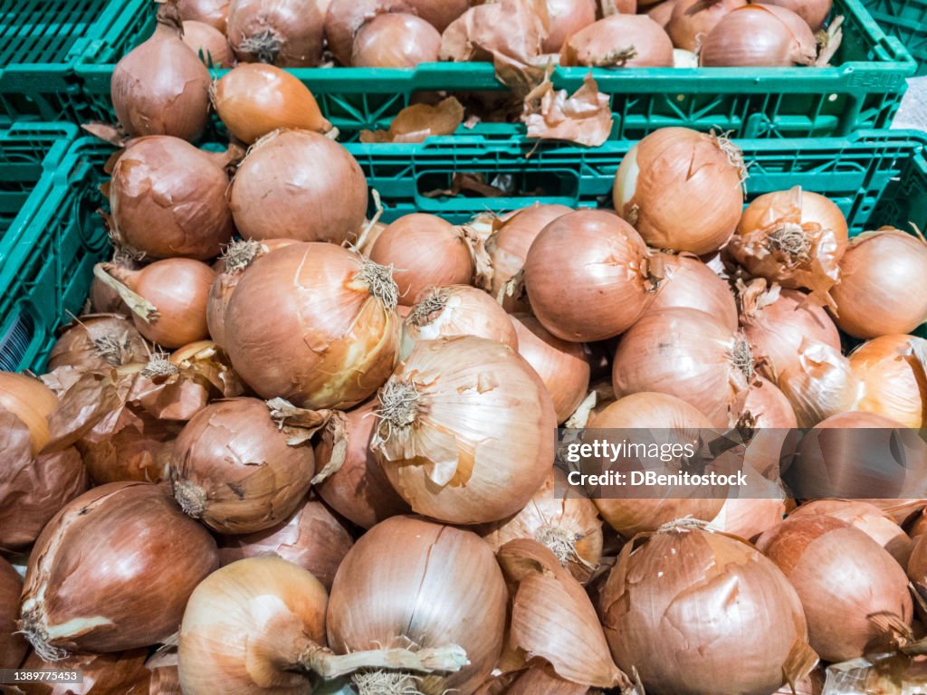 Piles of onions stacked in boxes in a supermarket. Concept of vegetables, ripe onions, sale, purchase, nutrition and healthy food.