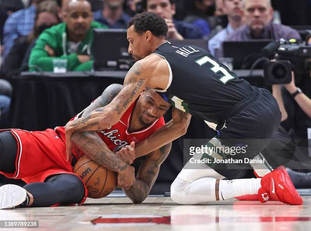 DeMar DeRozan of the Chicago Bulls and George Hill of the Milwaukee Bucks battle for a loose ball at the United Center on April 05, 2022 in Chicago,...