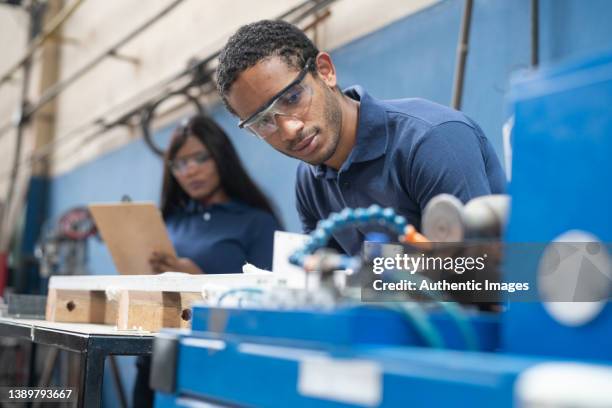 lavoratori multirazziali che utilizzano macchinari presso la fabbrica di pannelli solari - operaio di produzione foto e immagini stock