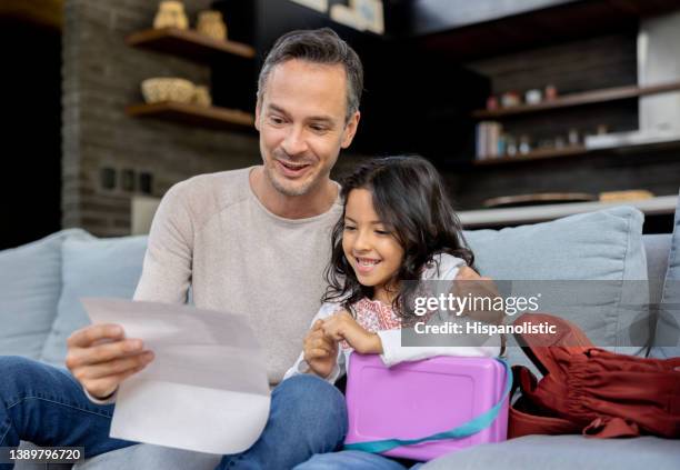 father looking very happy looking at his daughter's grades at home - proud parent stock pictures, royalty-free photos & images