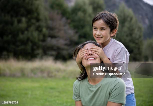 figlio amorevole che sorprende sua madre all'aperto e le copre gli occhi - mani sugli occhi foto e immagini stock