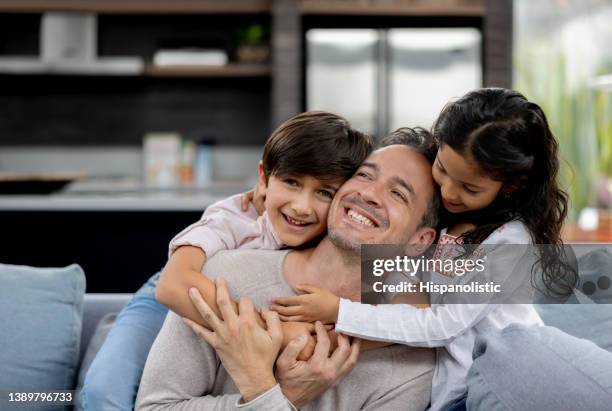 loving father at home hugging his children and looking very happy - povo espanhol e povo português imagens e fotografias de stock