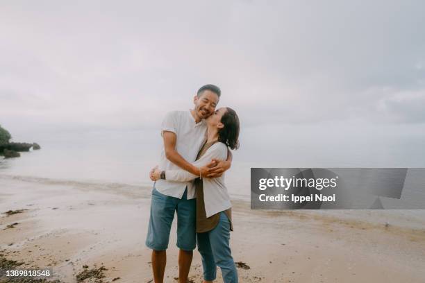 happy couple embracing each other on beach at dusk, japan - japanese couple beach stock-fotos und bilder