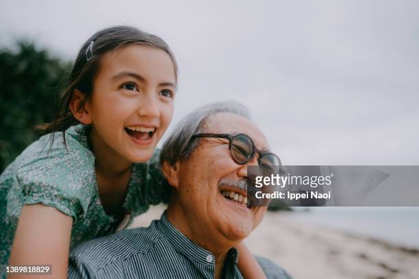 grandfather and granddaughter having a good time on beach at dusk - 子供　日本人　笑顔 ストックフォトと画像