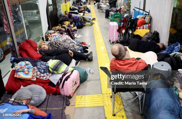 Ukrainians who are seeking asylum in the U.S. Sleep as they await their turn to cross the border at a makeshift encampment in a bus stop near the...