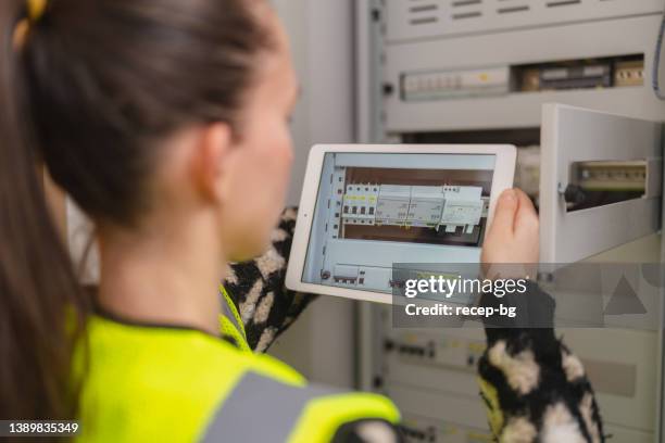 デジタルタブレットを使用し、家庭で電気パネルを固定する女性技術者 - electrical fuse ストックフォトと画像