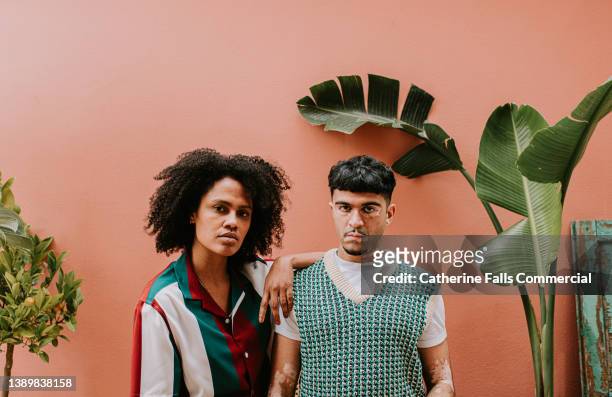 two young, fashionable models look confident as they stand beside each other and look at the camera - trade show stockfoto's en -beelden
