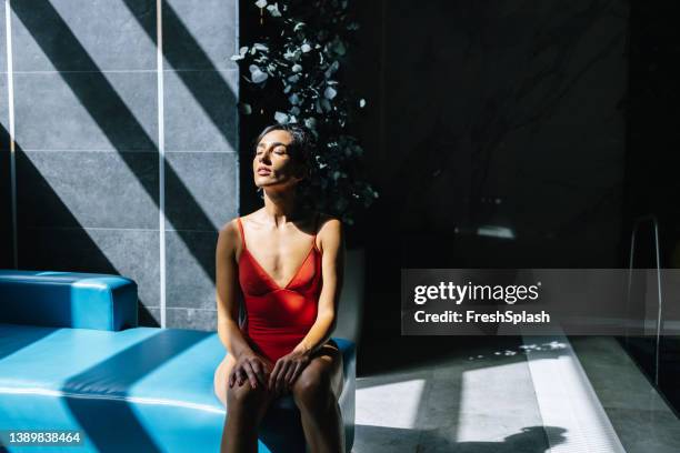 brunette sitting on the sofa in the spa center - red swimwear stock pictures, royalty-free photos & images