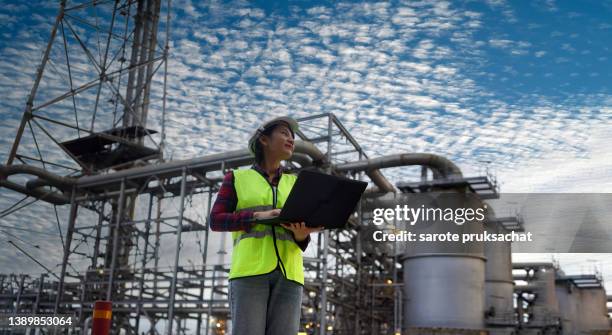 female engineer in the hard hat used tablet while working at the heavy petrochemical plant . - petroquimica imagens e fotografias de stock