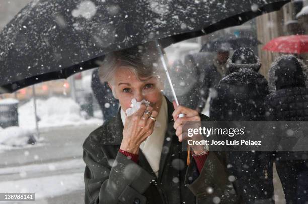 young woman wiping nose while walking in snow - hankerchief stock pictures, royalty-free photos & images