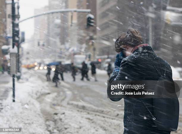 young woman communicating on cell phone in snow - blizzard photos et images de collection