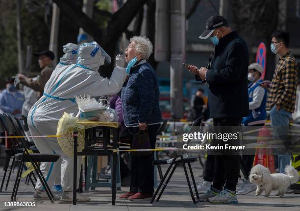 Health worker wears protective gear as she gives a nucleic acid test to detect COVID-19 on a local resident at a mass testing site after new cases...