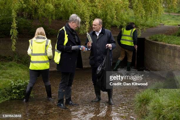 Liberal Democrat leader Ed Davey is shown a piece of previously collected rubbish while standing in the River Wandle at Wandle Park on April 06, 2022...