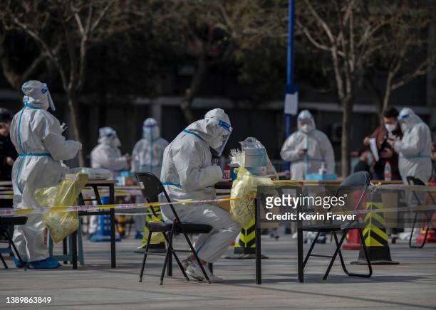 Health workers wear protective gear as they wait to give nucleic acid test to detect COVID-19 on local residents at a mass testing site after new...